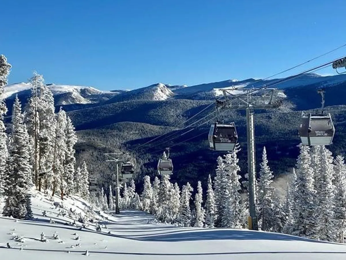 A scenic exterior view featuring ski lift gondolas gliding above snow-covered trees, with a majestic mountain range in the background. The landscape evokes both winter adventure and serene beauty.