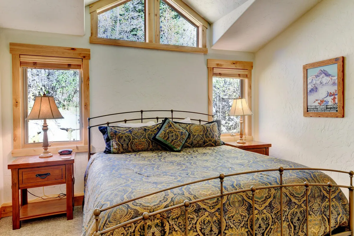 This image showcases a king suite with an ornate bed, large windows bathing the room in natural light, bedside lamps, and tasteful wall art. The tranquil, comfortable mood invites relaxation and rest, perfectly aligning with the narrative of restful master suites curated for rejuvenation.
