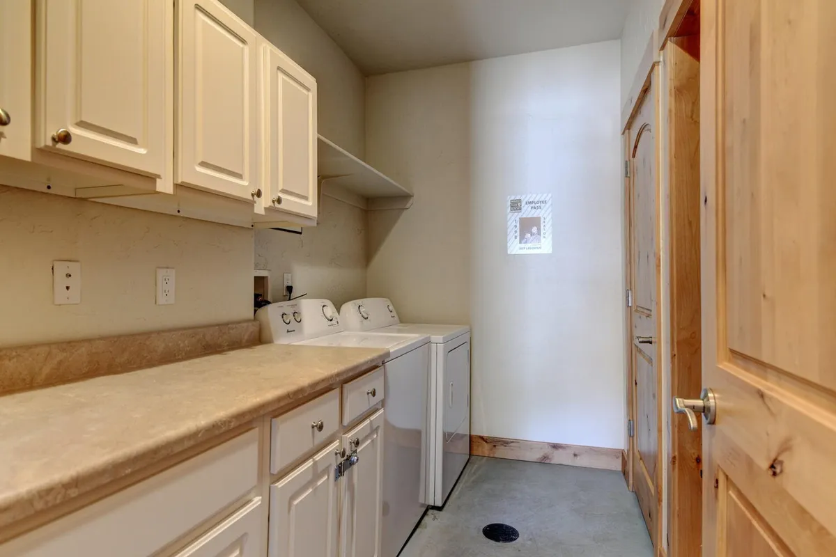 A tidy laundry space featuring a washer and dryer, a countertop for folding clothes or organizing supplies, and a wooden door. The scene is practical and organized, supporting family needs after mountain excursions.